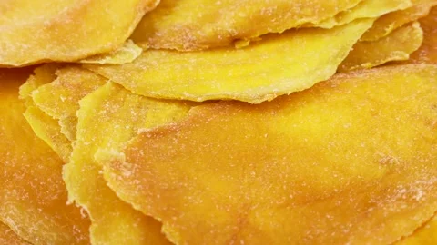 Bright yellow dried mango slices rotation close up Stock Footage 240668032