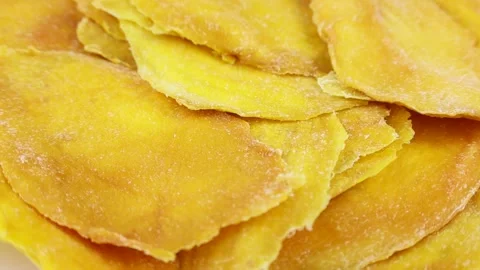 Bright yellow dried mango slices rotation close up Stock Footage 243560430