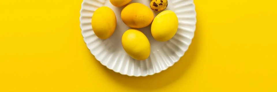 Bright yellow Easter eggs and speckled quail eggs are beautifully arranged on Stock Photos