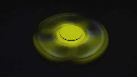 Bright yellow fidget finger spinner on dark background Stock Footage 78240865