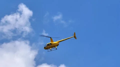 A bright yellow helicopter flying through a clear blue sky Video stock 341933237