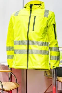 Bright yellow high-visibility jacket on a mannequin, indistinct pattern backd Stock Photos