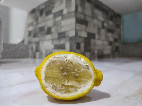 Bright yellow lemon cut in half rests on white surface Stock Photos