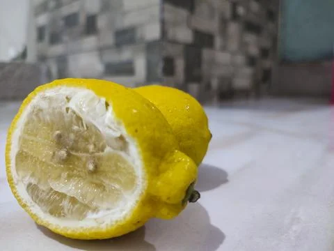 Bright yellow lemon cut in half rests on white surface Stock Photos