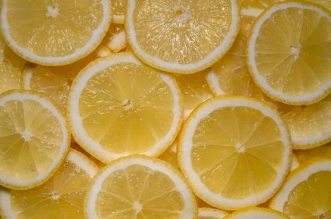 Bright yellow lemon slices create a vibrant and refreshing pattern for culi.. 库存照片