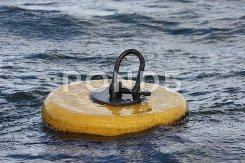 A bright yellow mooring buoy with shackle on top Stock Photos