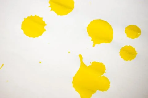 Bright yellow paint splashes of various sizes scattered on a white. Stock Photos