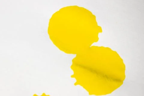 Bright yellow paint splashes of various sizes scattered on a white. Stock Photos