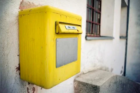 A bright yellow post box on the wall, close up. Foto stock