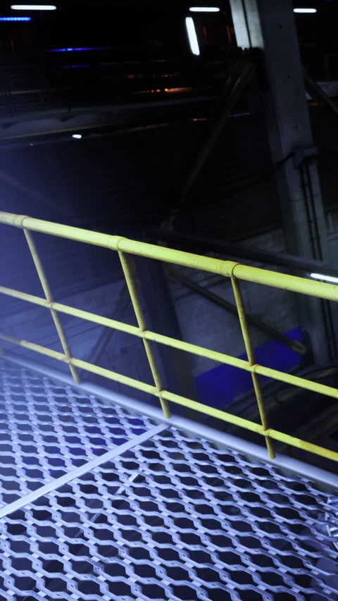 Bright yellow railing contrasts with dark industrial scene in vibrant setting Stock Footage 331840277
