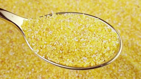 Bright yellow small corn grits in the spoon with circle rotation close up Stock Footage 240663883