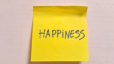 Bright yellow sticky note featuring the word happiness hand written clearly Stock Photos
