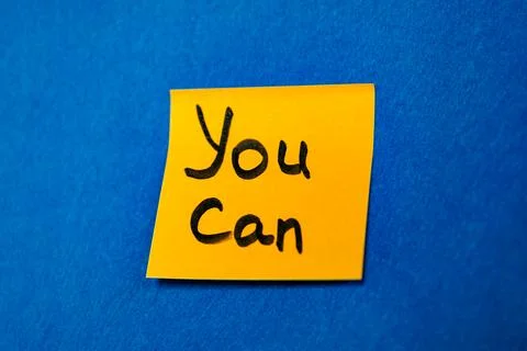 Bright yellow sticky note with handwritten phrase You Can on blue felt backgroun Stock Photos