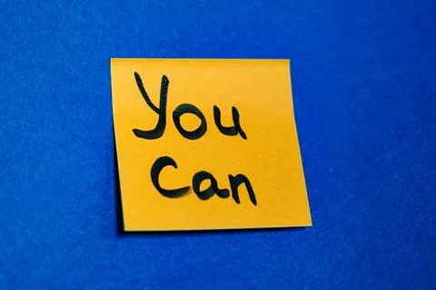 Bright yellow sticky note with handwritten phrase You Can on blue felt backgroun Stock Photos