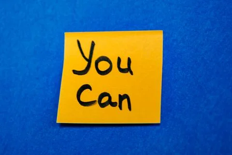Bright yellow sticky note with handwritten phrase You Can on blue felt backgroun Stock Photos