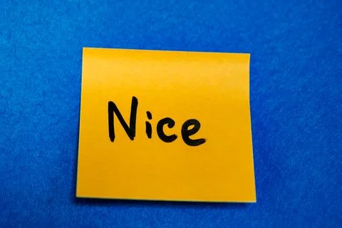 Bright yellow sticky note with handwritten word Nice on blue felt background, pr Stock Photos