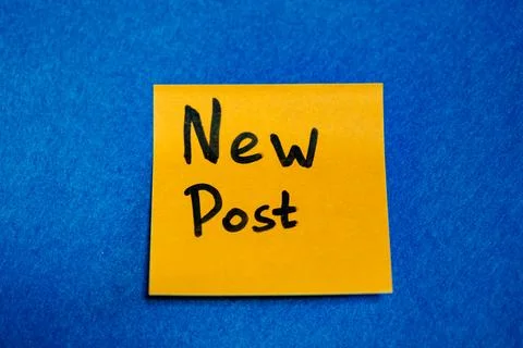 Bright yellow sticky note with handwritten phrase New Post on blue felt backgrou Stock Photos