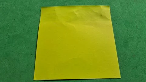 Bright yellow sticky note paper square on a green background Stock Photos