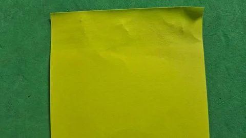 Bright yellow sticky note paper placed on a textured green surface Stock Photos