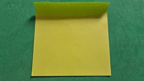 Bright yellow sticky note placed on a dark green paper background Stock Photos