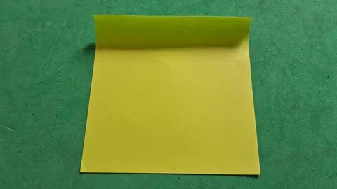 Bright yellow sticky note placed on a dark green textured surface Stock Photos