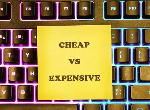 A bright yellow sticky note with the words cheap and expensive is on a comput Stock Photos