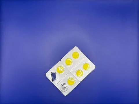 Bright yellow tablets in silver packaging on a bright blue background in the Stock Photos