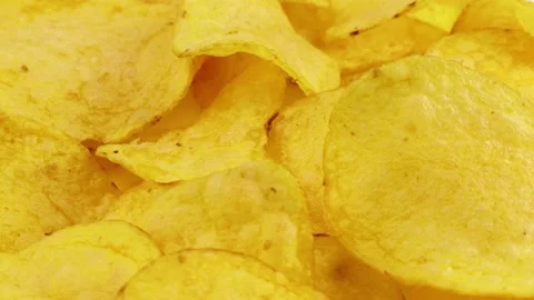 Bright yellow thin potato chips texture circle rotation close up Stock Footage 233998019