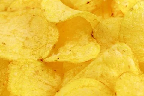 Bright yellow thin potato chips as a textured food background close up Stock Photos