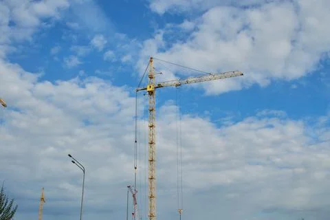 A bright yellow tower crane operating at a construction site of a modern mult Stock Photos