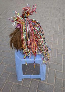 Brightly colored African braiding patterns displayed on a blue stool in a S.. Stock Photos