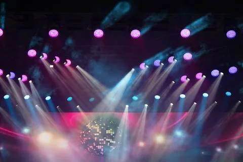 Brightly colored beams of light shine across the venue as a disco ball reflec Stock Photos