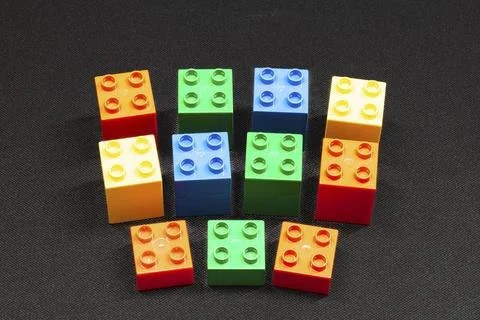 Brightly colored bricks scattered on dark textured surface Stock Photos