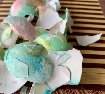 Brightly colored easter egg shells rest on a wooden surface, creating a vibrant Stock Photos