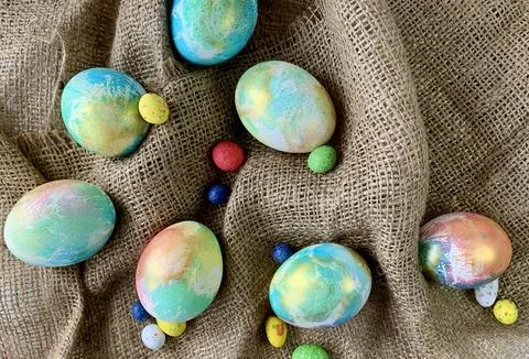 Brightly colored Easter eggs and colorful candy scattered on burlap fabric Foto stock
