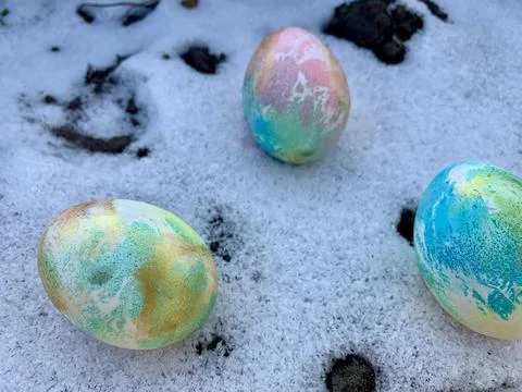 Brightly colored easter eggs are placed on a snowy surface, contrasting against Stock Photos
