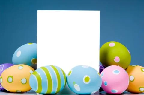 Brightly colored easter eggs surrounding white, blank notecard Stock Photos