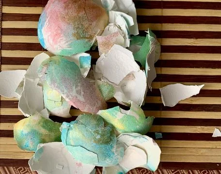Brightly colored eggshells are spread across a wooden surface, remnants of a Foto stock