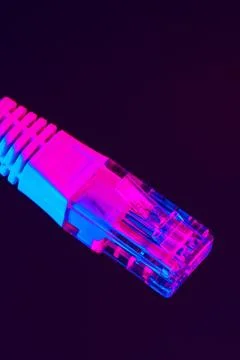 Brightly colored ethernet cable against dark background showing network Stock Photos