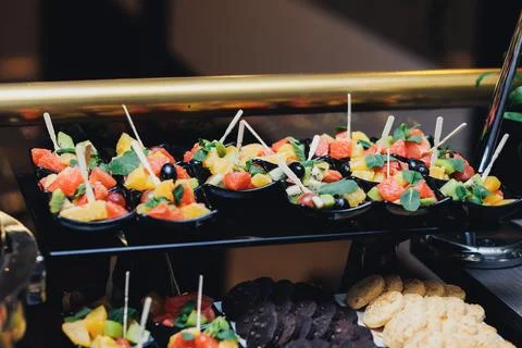 Brightly colored fruit cups sit neatly on a black tray Foto stock