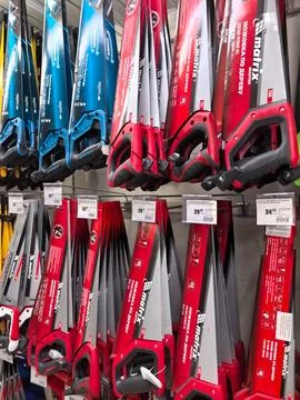 Brightly colored hand saws displayed in a hardware store aisle Photos