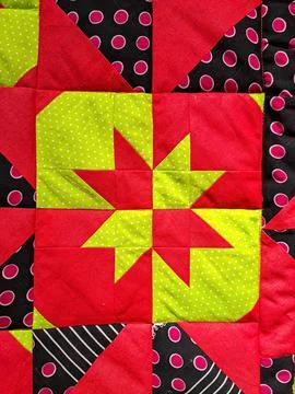 Brightly colored handmade patchwork quilt with a star design made of polka .. Stock Photos