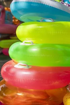 Brightly colored inflatable pool floats are stacked together, creating a vi.. Stock Photos
