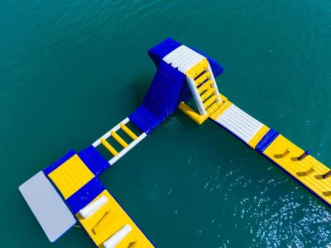 Brightly colored inflatable structures float on the water. People can climb,  Stock Photos