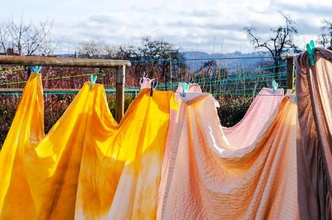 Brightly colored laundry drying on a clothesline in the sunshine with a hil.. Stock Photos