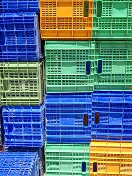 Brightly colored plastic fruit crates stacked in an outdoor market during d.. Foto stock