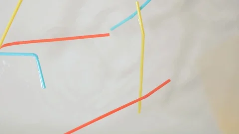 Brightly colored plastic single use straws dropping into water Stock Footage 93960764