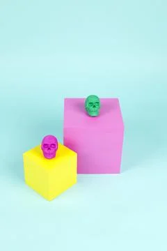 Brightly colored plastic skulls on pink and yellow cubes Stock Photos