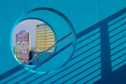 Brightly colored wall with round windows and shadow from a railing Stock Photos