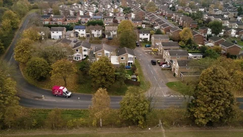 Brightly coloured delivery van drives through residential area, drone aerial 4K Stock Footage 101169399